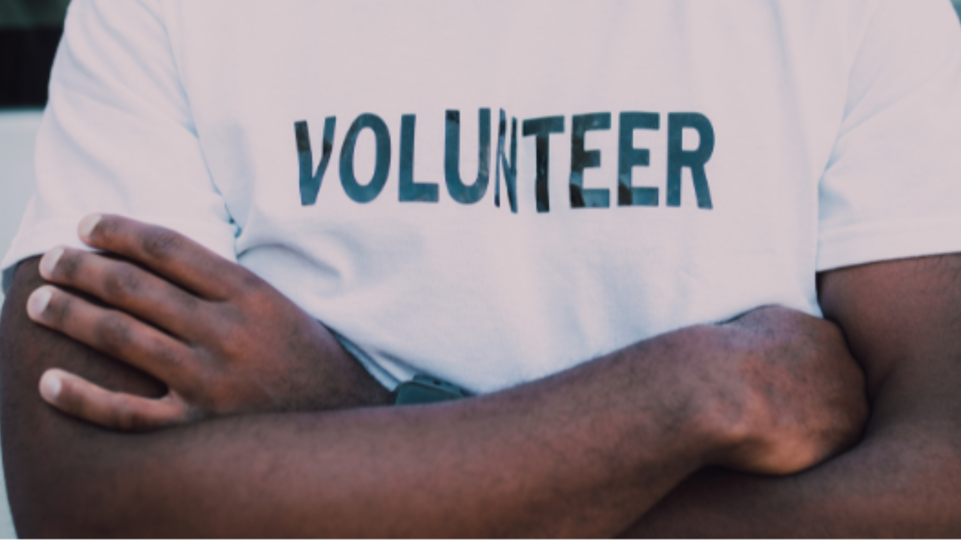 Person with arms crossed wearing a volunteer tshirt